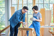© Bangkok Click Studio - Asian professional carpenter engineer dad teaching young boy son in jeans outfit with gloves safety goggles  in home housing building construction site.