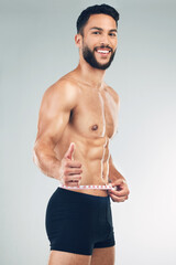 Poster - Body, waist and thumbs up with a man model in studio on a gray background to promote weightloss or exercise. Portrait, fitness and diet with a young male measuring for health, success or motivation