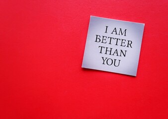 Card on red background with handwritten I AM BETTER THAN YOU - means SUPERIORITY COMPLEX, people who have belief that your abilities or accomplishments are dramatically better than someone else