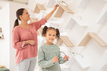 Poster - Optometry, mother and child with decision on glasses for vision, smile and help with eyes at a clinic. Happy, consulting and girl kid patient at the optometrist for eyeglasses with her mom helping