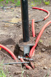 © Lyubov - wires and insulation hoses stick out of the ground next to a lamppost, vertical shot.