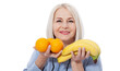 © missty - Happy woman with blond hair and beautiful smile holds two oranges and a bananas in her hands for a healthy diet with vitaminswith. Concept healthy food fruits