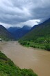 Vertical of a river flowing through the mountains under a cloudy sky.