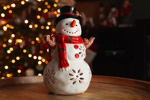 Ceramic Snowman Figurine. Beautiful, Festive Toy Decoration For Christmas And Winter, With Tree Lights Bokeh In Background.