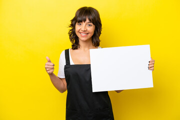 Wall Mural - Restaurant waiter latin woman isolated on yellow bakcground holding an empty placard with thumb up