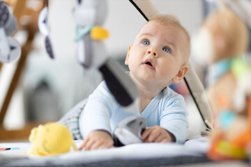 cute baby boy playing with hanging toys arch on mat at home baby activity and play center for early 