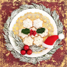 Christmas Homemade Mince Pies With Winter Holly On White Plate, Santa Hat And Tree Bauble Decorations On Red Grunge Background. Festive Food Design For Xmas And New Year Holiday.