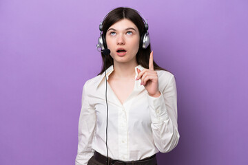 Wall Mural - Telemarketer Russian woman working with a headset isolated on purple background thinking an idea pointing the finger up