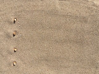 Aufkleber - Four cigarette butts arranged as bullet points in sand on beach