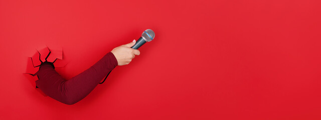 microphone in hand over red background, panoramic layout