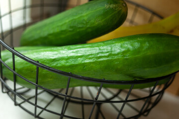 Wall Mural - Two green cucumbers in a metal basket