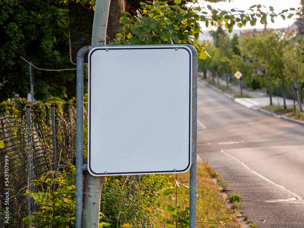 Empty sign next to a street. Blank white metal plate to show an ...