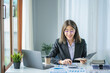 © ArLawKa - Asian businesswoman analyzing financial charts using laptop calculator and smartphone at office