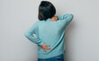© My Ocean studio - Spinal cord problems on woman's back. Chronic back pain. Young brunette woman is holding her lower back and neck, while standing and suffering from unbearable and severe pain. Spine osteoporosis.