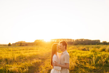 Wall Mural - loving young couple hugging and kissing with closed eyes enjoying each other on green field in summe
