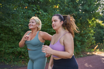 Two happy girls running with each other at the morning through the summer park