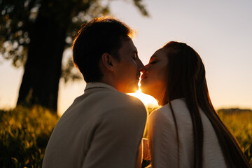 Wall Mural - close-up silhouette view of beautiful young couple in love sitting hugging and kissing enjoying thei