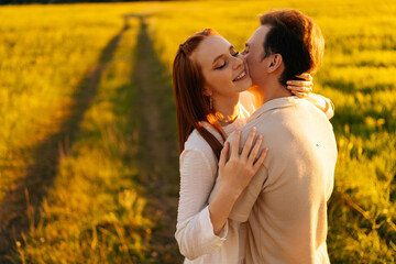 Wall Mural - happy young couple in love with closed eyes hugging, kissing, stroking standing together on green me