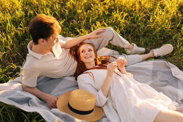 high-angle view of happy smiling young couple in love lying together looking at each other on sunny 