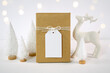Christmas gift tag party favor thank you card mockup, styled with white reindeer and mini trees, bokeh party fairy lights on a minimalist white background.