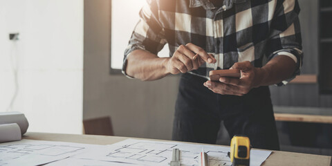 Wall Mural - Image of engineer drawing a blue print design building or house, An engineer workplace with blueprints, pencil, protractor and safety helmet, Industry concept