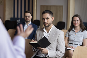 Sticker - Unrecognizable presenter make speech standing in front of participants noting received information looking interested, motivated to develop their skills during educational business seminar in office