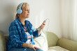 © evafesenuk - Profile of a senior woman in headphones sitting on the couch listening to music