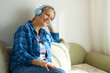 © evafesenuk - Portrait of a mature smiling woman in blue headphones listening to music