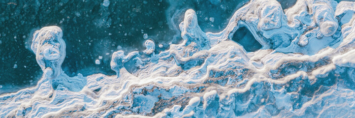 Winter aerial photograph of the icy coast and ice floes in sea water. Top view of the freezing sea. Northern nature. Frosty winter weather. Cold arctic climate. Beautiful wide panoramic background.