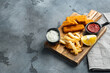 Fried fish finger stick or french fries fish with sauce, on wooden cutting board, on gray background , with copyspace  and space for text
