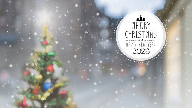 Christmas and Happy new year 2023 on blurred bokeh Christmas tree with snowfall banner background.