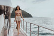 Beautiful caucasian woman wearing bikini and walking on yacht. Young sexy female smiling and enjoying in cruise ship on vacation trip, lady slim model in swimwear.