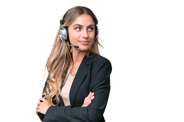 Wall Mural - Telemarketer pretty Uruguayan woman working with a headset over isolated background with arms crossed and happy