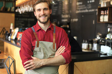 Male Business Owner Behind The Counter Of A Coffee Shop With Crossed Arms, Looking At Camera.