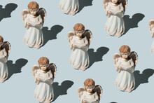 Statues Of Angels Praying On A Blue Background. Christmas Pattern