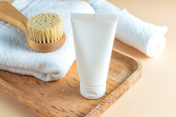 Poster - White tube mockup for cosmetic products and various bath care accessories - face brush with natural bristle, cotton towels on wooden tray, Spa treatment concept