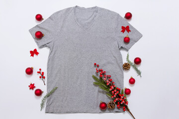 Close up grey blank template t shirt with copy space and Christmas Holiday concept. Top view mockup t-shirt and red holidays decorations on white background. Happy New Year accessories. Xmas outfit