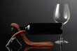 Bottle of red wine in a wooden bottle holder and an empty glass.