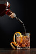  Whiskey is poured into a glass with ice and orange peel.