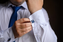 Portrait Of A Fashionable Man Fastening Stylish Cufflinks On The Sleeves Of His White Shirt. Wedding Day Concept.