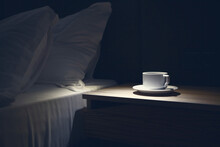 Bedside Table With White Mug Against The Bed At Night Time. Copy And Paste, Nobody