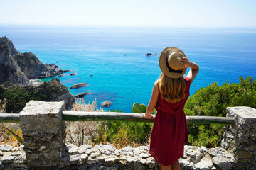 Wall Mural - Beautiful young woman with hat looking at stunning panoramic view of Capo Vaticano on Coast of the Gods, Calabria, Italy