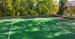 Aerial video of a new green and red outdoor basketball court at school playground or part.  Court includes retaining walls and black vinyl coated chain link fence.	