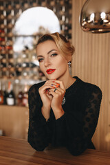 Portrait of a blonde woman in a black vintage dress sitting in a cafe