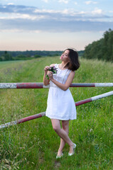 Wall Mural - Young woman in white dress standing in the nature with bouquet of flowers on a beautiful summer day