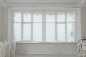 Canvas Print - Windows covered by plastic film and building materials in renovated room