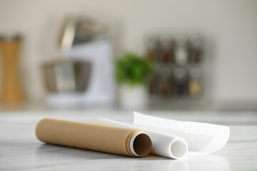 Wall Mural - Rolls of baking paper on white marble table against blurred background indoors. Space for text