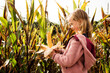© Cavan Images - girl holding a corn on the cob in a maize field in autumn