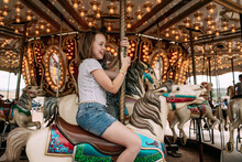 Young Girl Riding A Carousel Outside