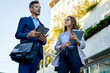 © Cavan Images - Young business partners talking in front of office building